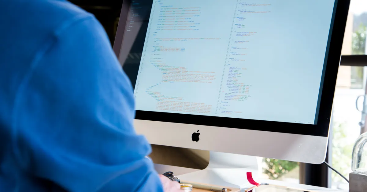 Un desarrollador de software escribiendo código en un puesto de trabajo con ordenador