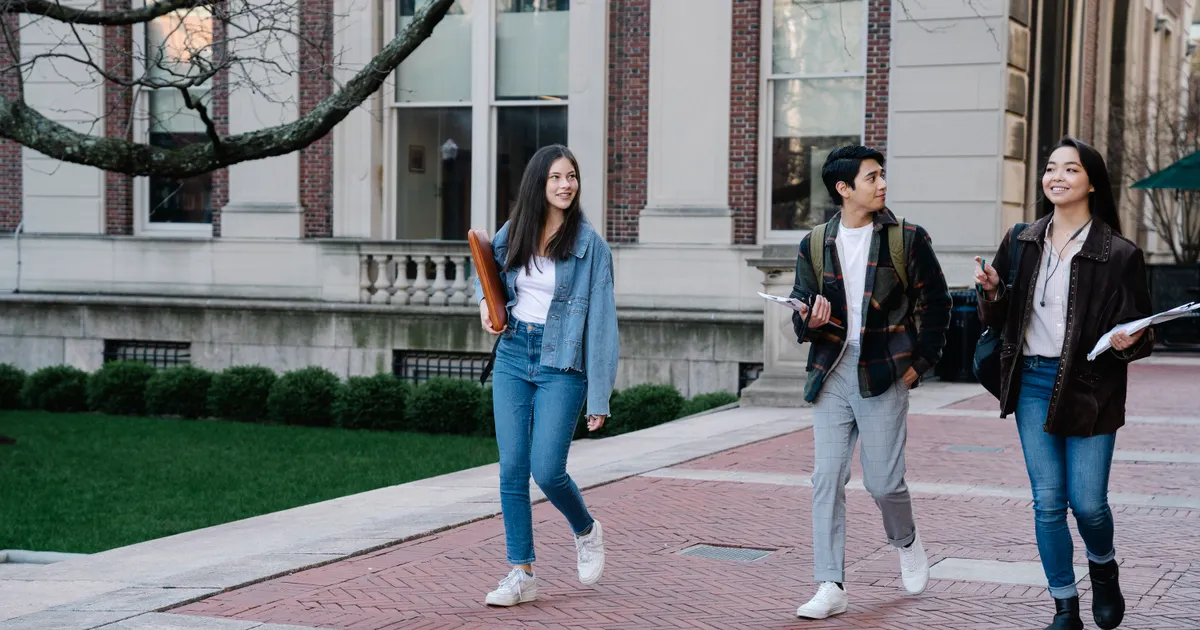 Studierende, die gemeinsam über einen Innenhof auf dem Campus gehen