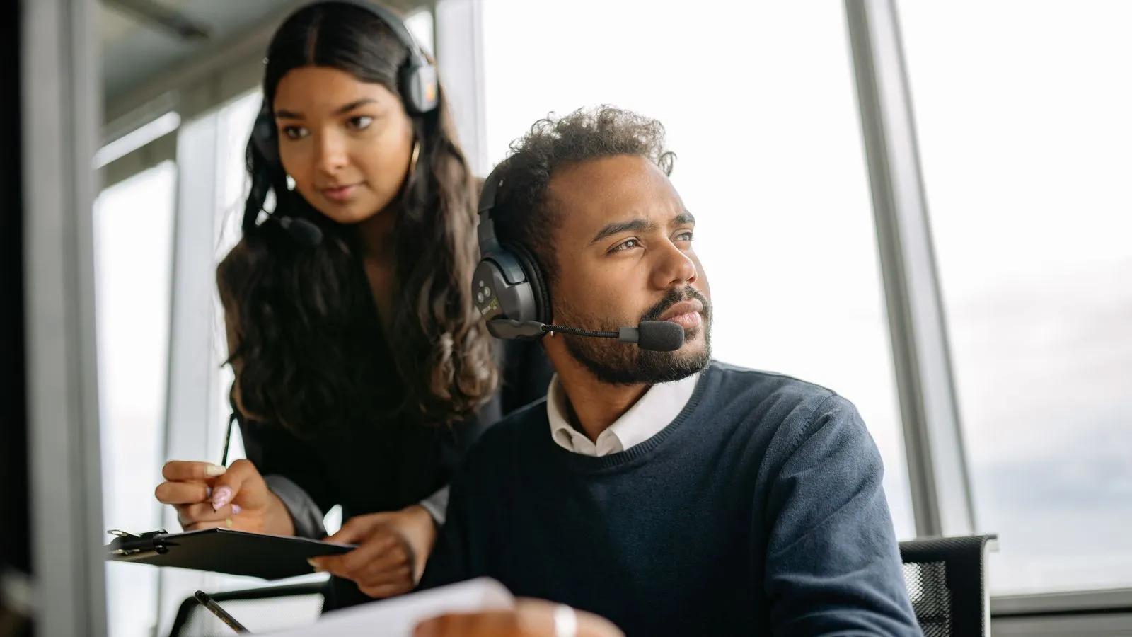 Two B2B sales professionals running outbound prospecting calls with headsets in an office
