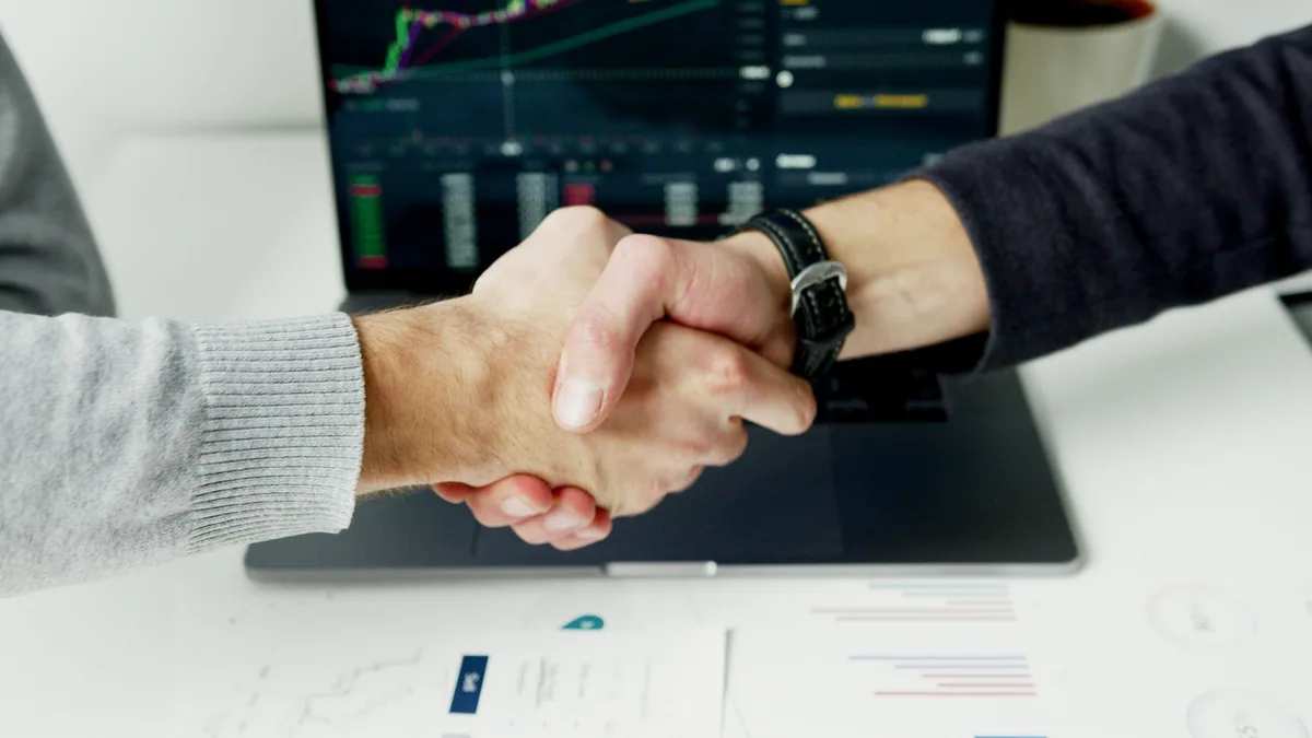 Close-up of a handshake over financial charts, illustrating the ranking of the best affiliate marketing agencies in France