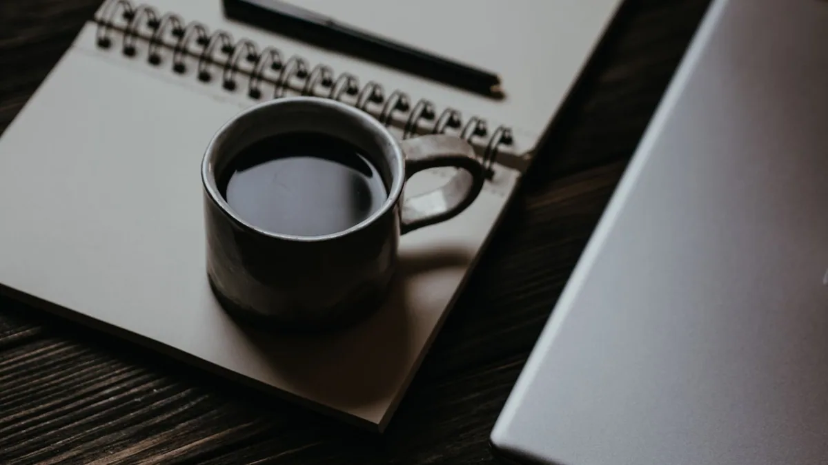 Notebook, coffee cup and laptop on a writing desk, illustrating the ranking of the best content marketing agencies in France