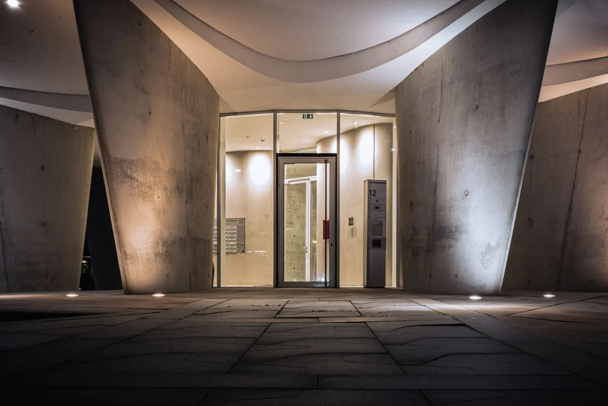Glass entrance of a modern concrete building lit at night