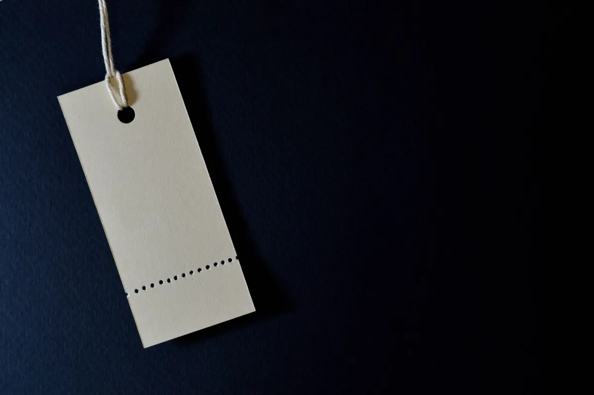 Blank paper tag hanging from a white string against a dark blue background