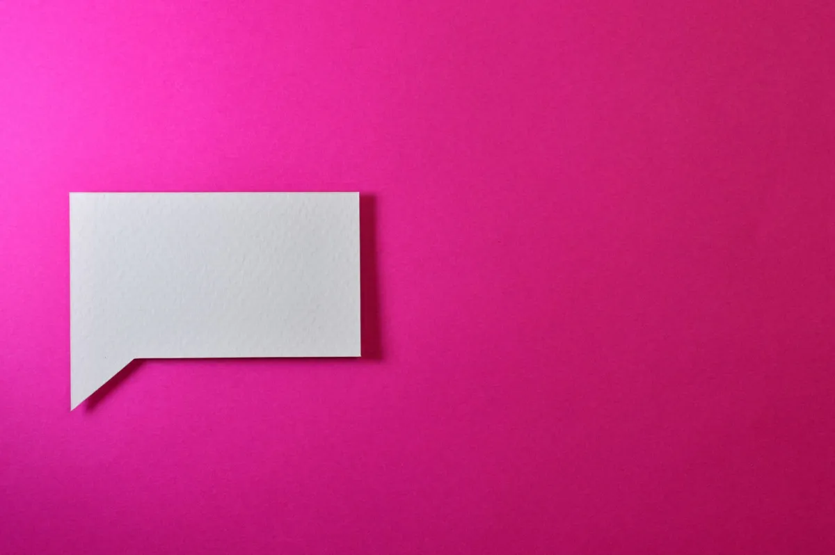 Blank white paper speech bubble on a bright pink background