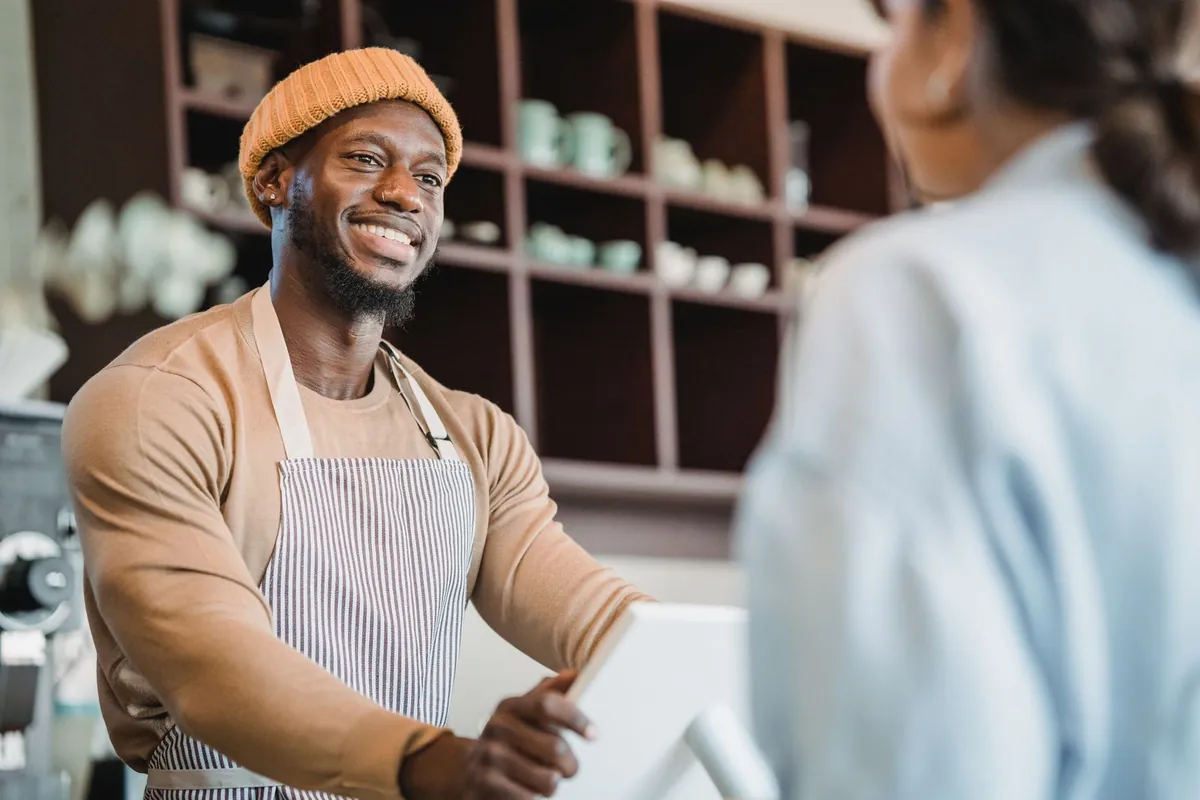 Smiling barista taking an order from a customer at a cafe counter