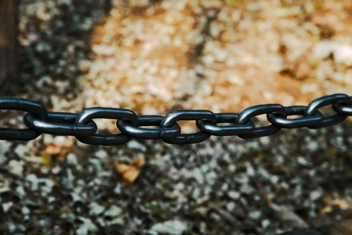 Close-up van een zwarte metalen ketting waarvan de schakels in elkaar grijpen