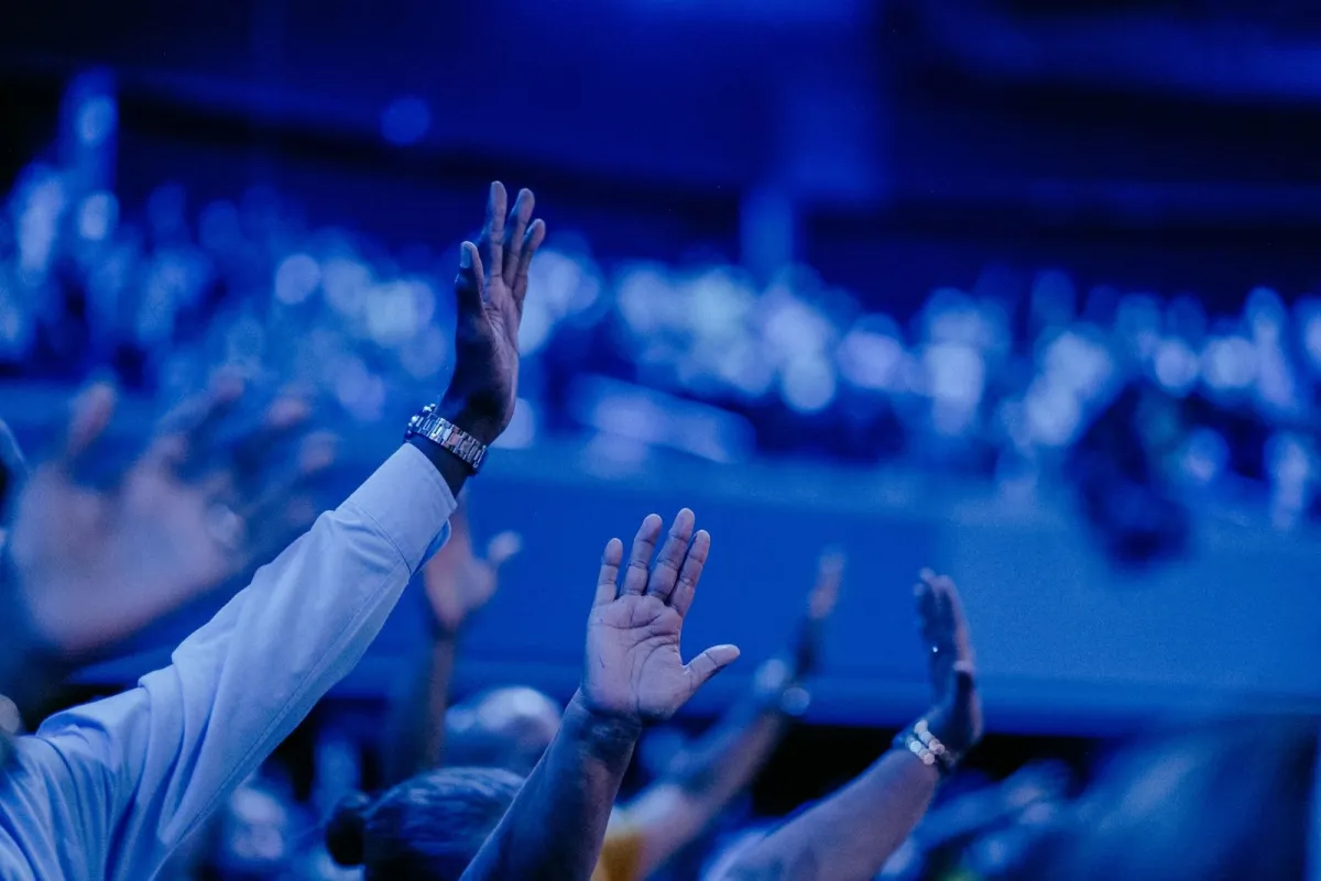 Audience raising their hands under blue stage lights