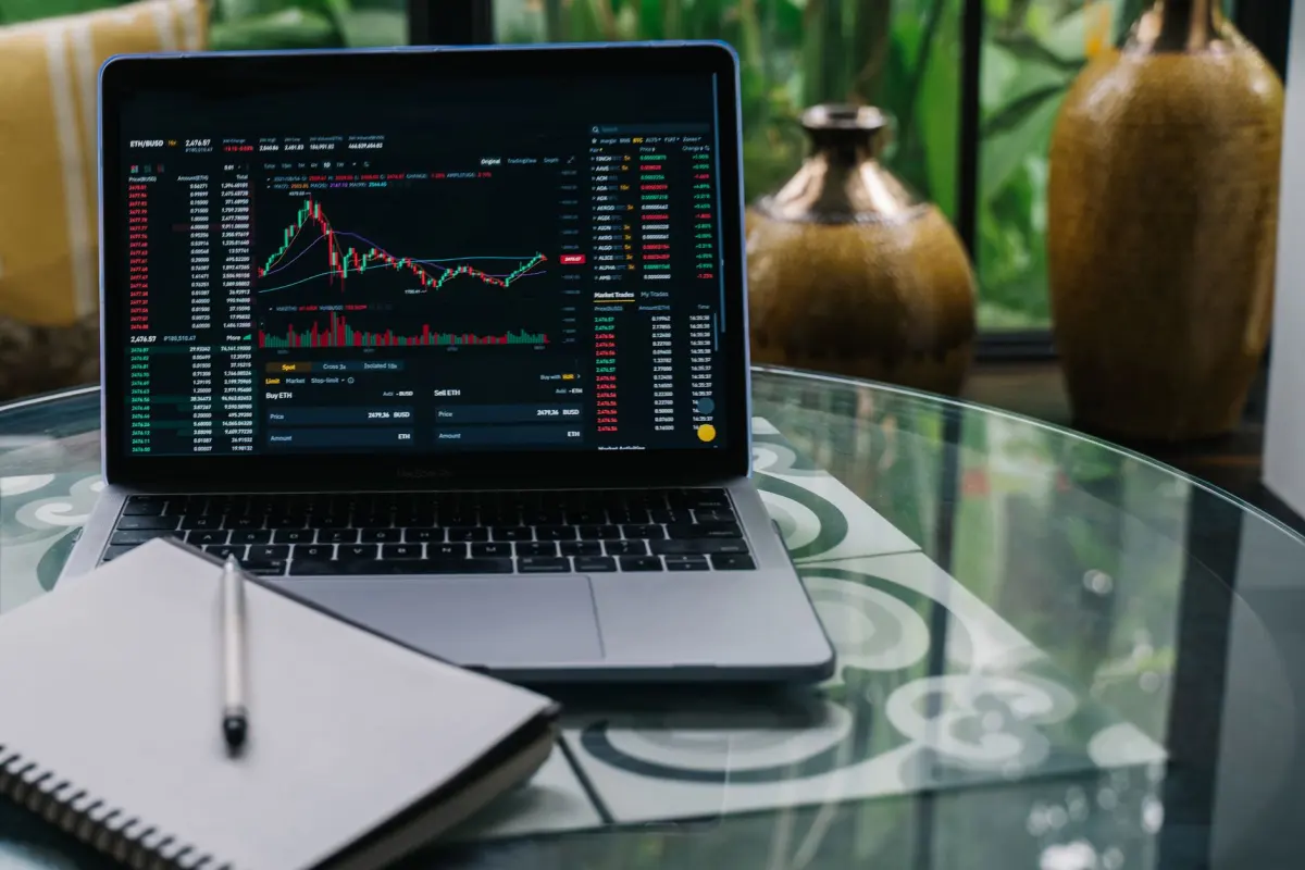 Laptop showing traffic charts on a desk next to a notebook