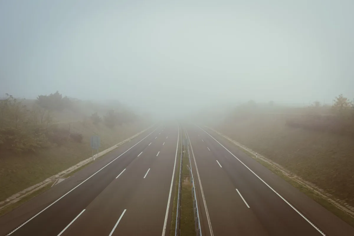 Empty highway disappearing into thick fog