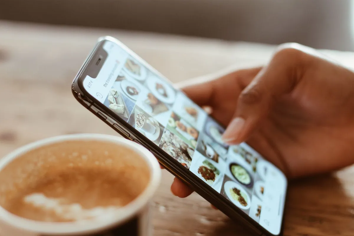 Hand photographing a restaurant dish with a smartphone to post it online, illustrating the ranking of the best social media management tools in 2027