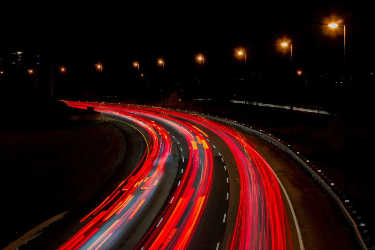 Long exposure of red light trails on a curving highway at night