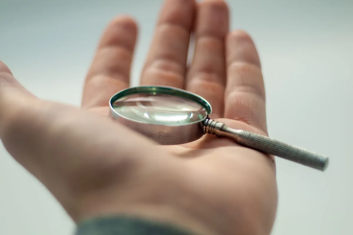 Open hand holding a small magnifying glass