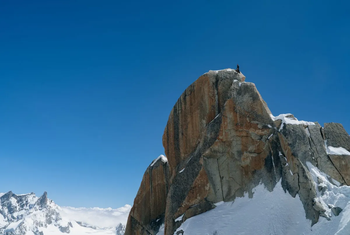 Climber standing on top of a snowy rock peak