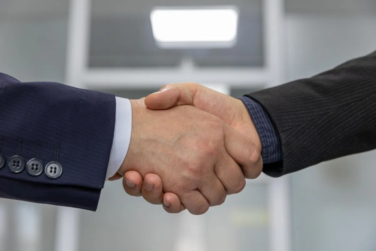 Close-up of two people in suits shaking hands
