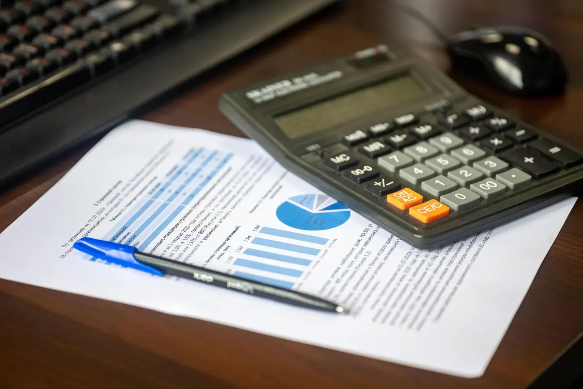 Calculator and pen on a printed marketing report with charts