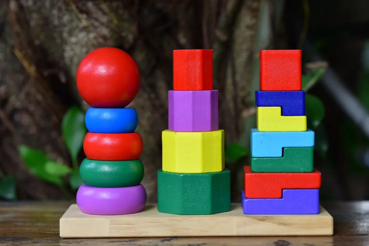 Colorful wooden stacking toys sorted by shape on a wooden base
