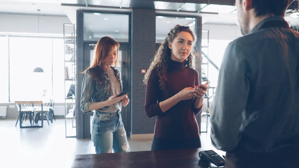 Jongvolwassenen die hun telefoon checken aan een cafébar