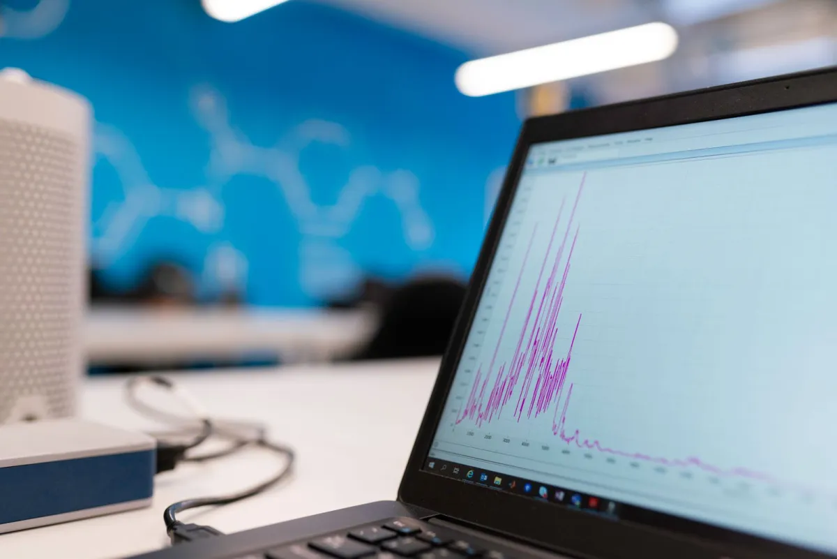 Laptop di meja kantor yang menampilkan grafik garis data