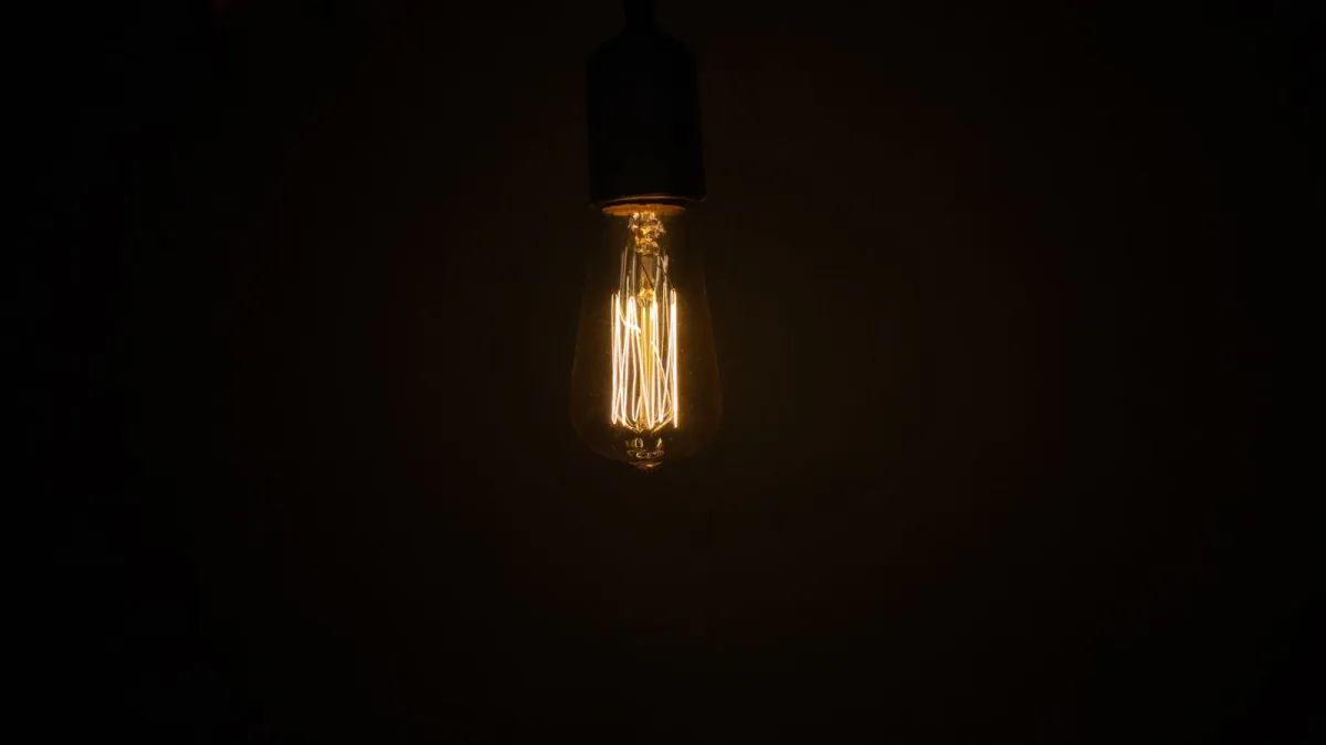 Single glowing light bulb hanging in the dark
