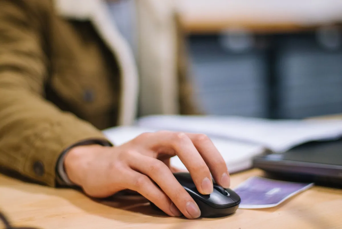 Hand clicking a wireless computer mouse on a desk