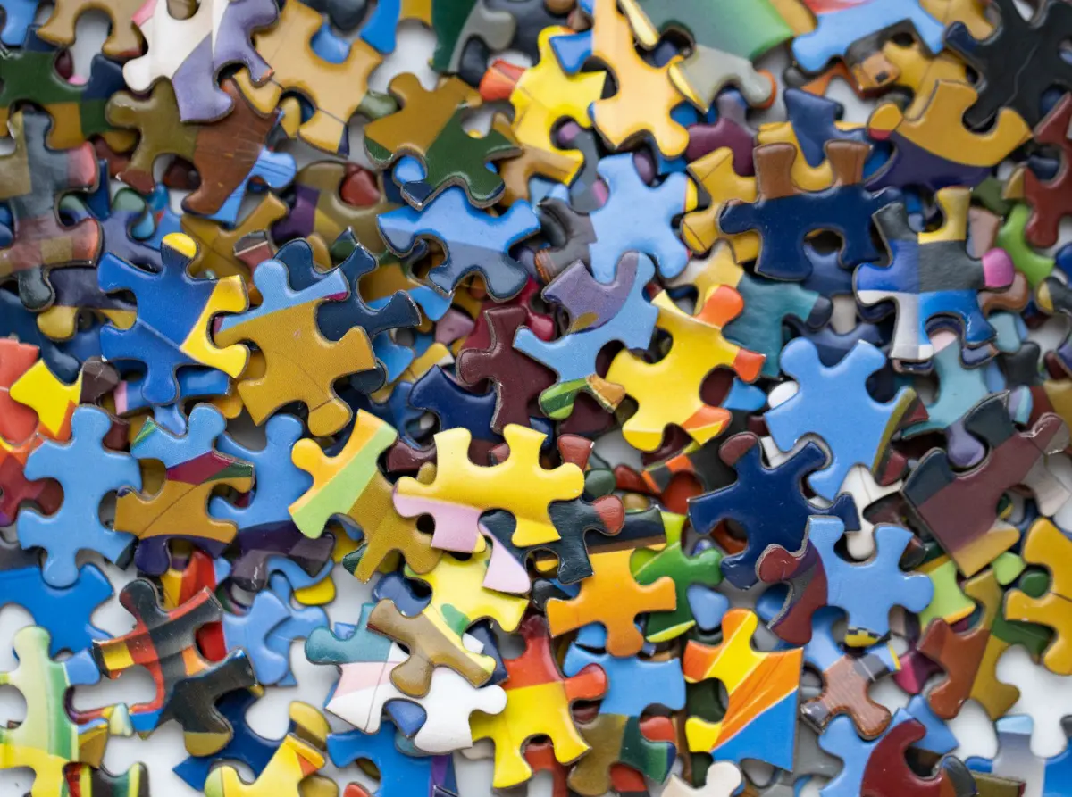 Hundreds of colorful jigsaw puzzle pieces scattered on a table