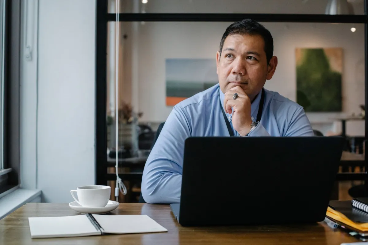 Manager thinking about a plan in front of his laptop in a bright office