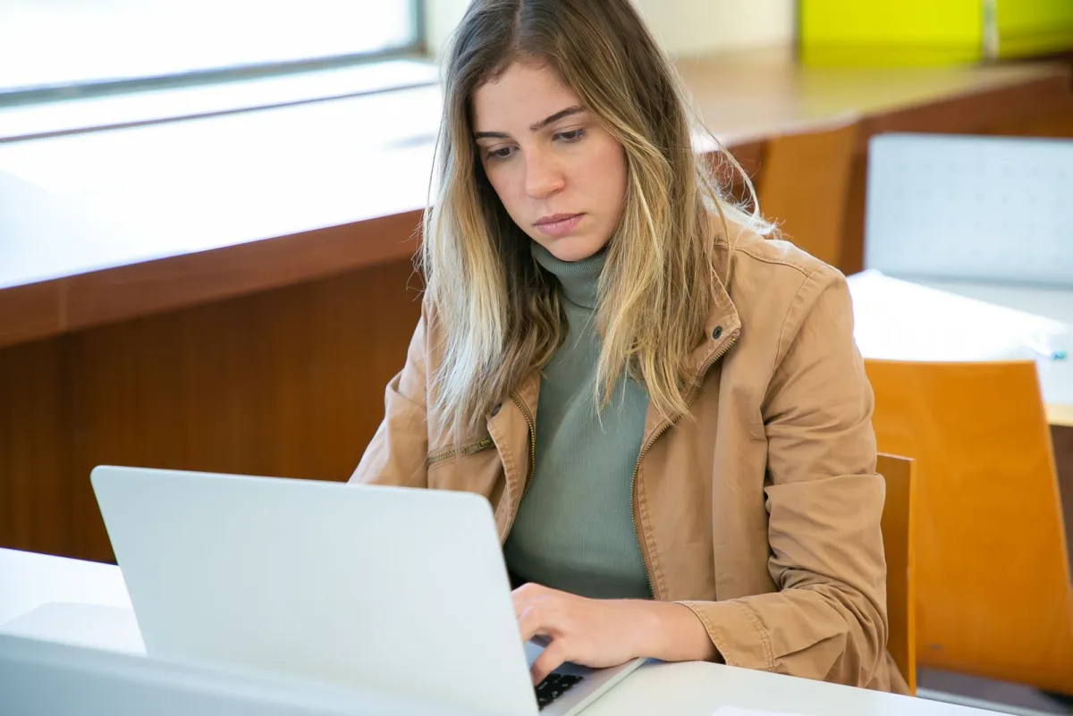 Freelancer browsing on a laptop at a table while working on a project