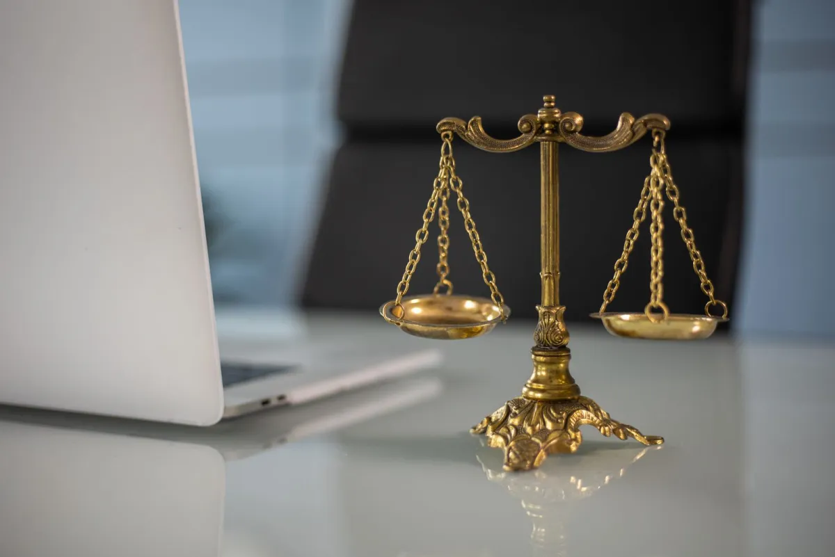 Gold balance scale on a white desk next to a laptop