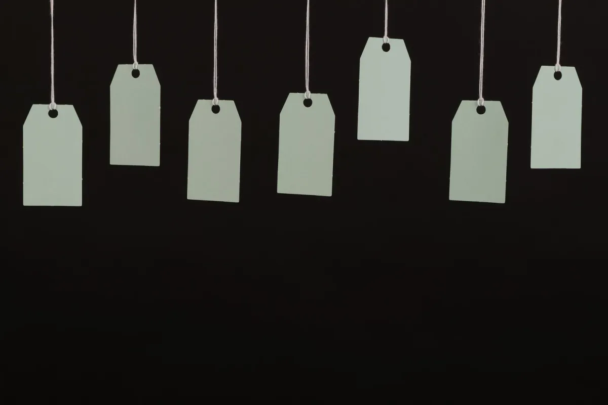 Blank paper tags hanging on strings against a dark background
