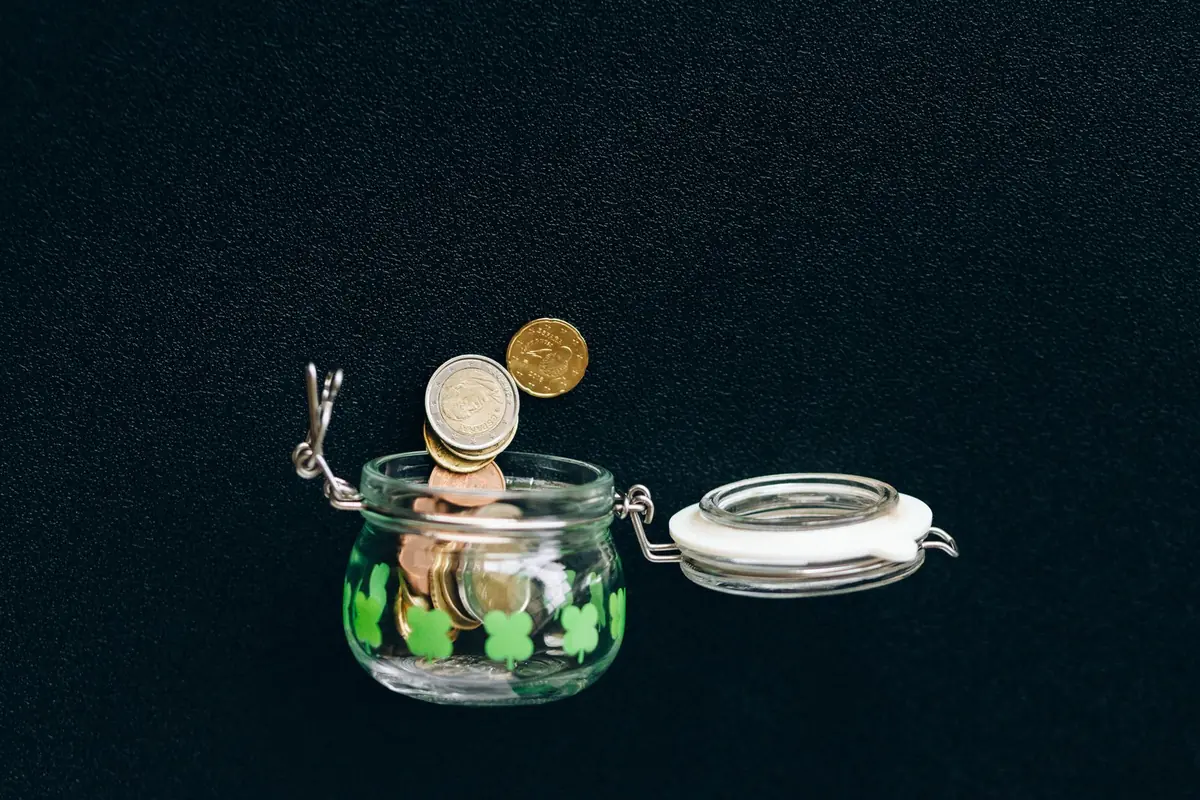 Coins falling into a glass jar on a black background