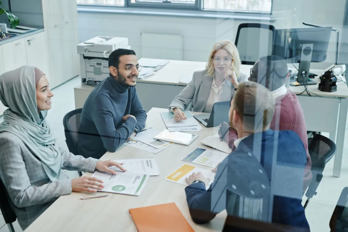 Team gathered around a desk reviewing documents in a bright office