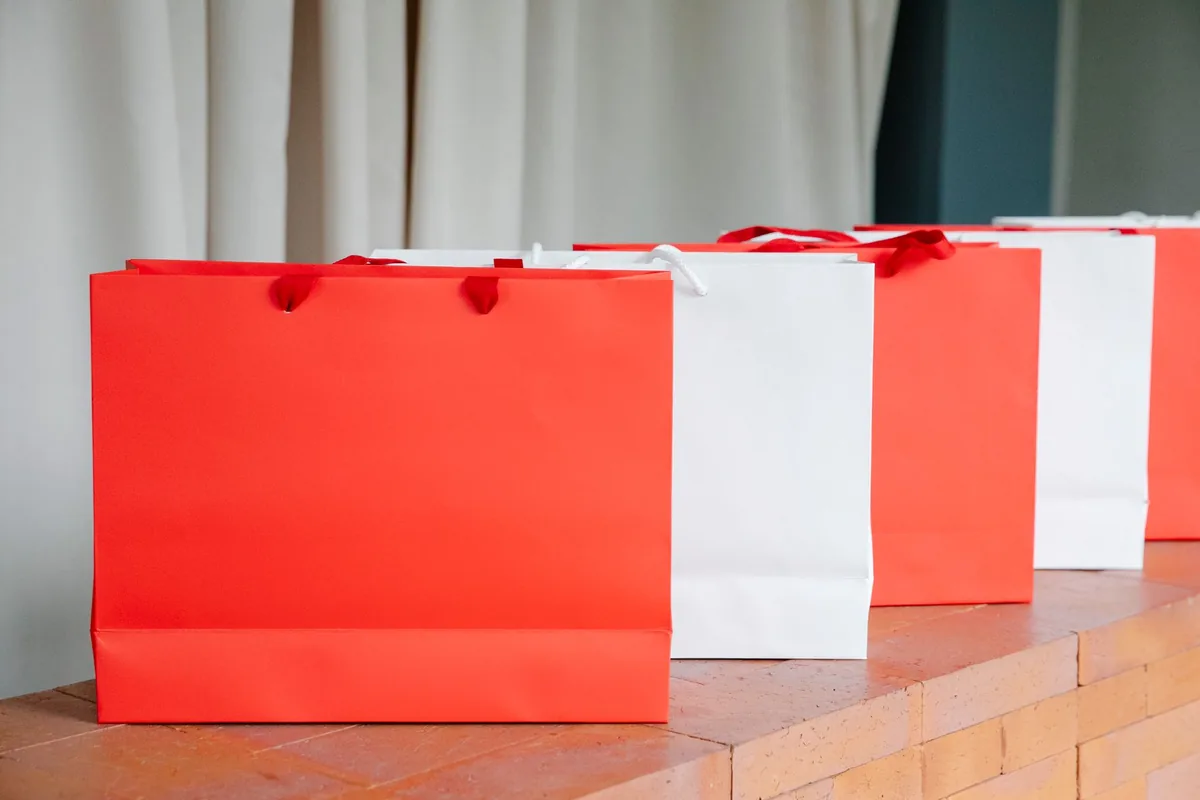 Row of red and white paper shopping bags on a wooden counter