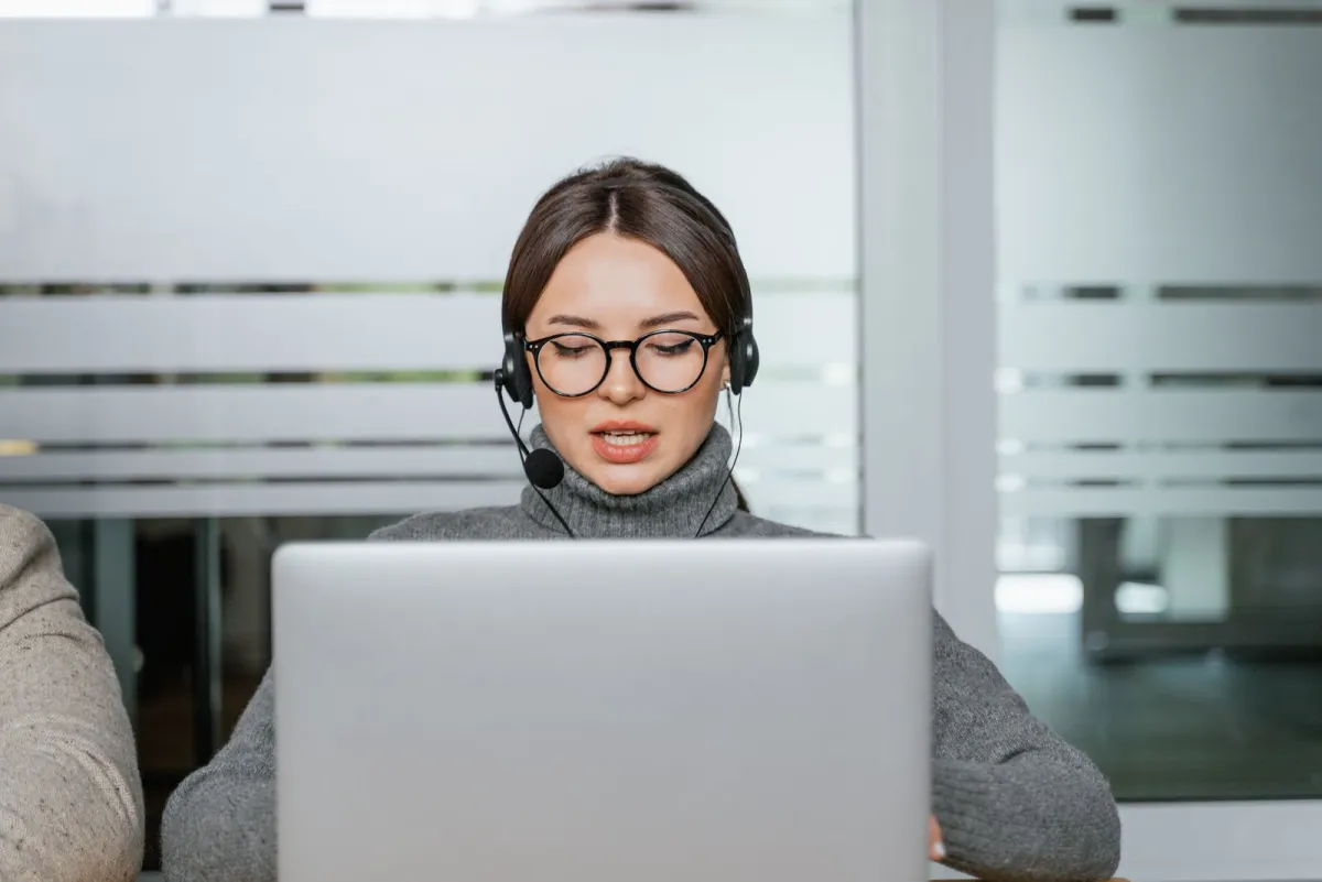 Sales representative with a headset talking to a prospect at her laptop