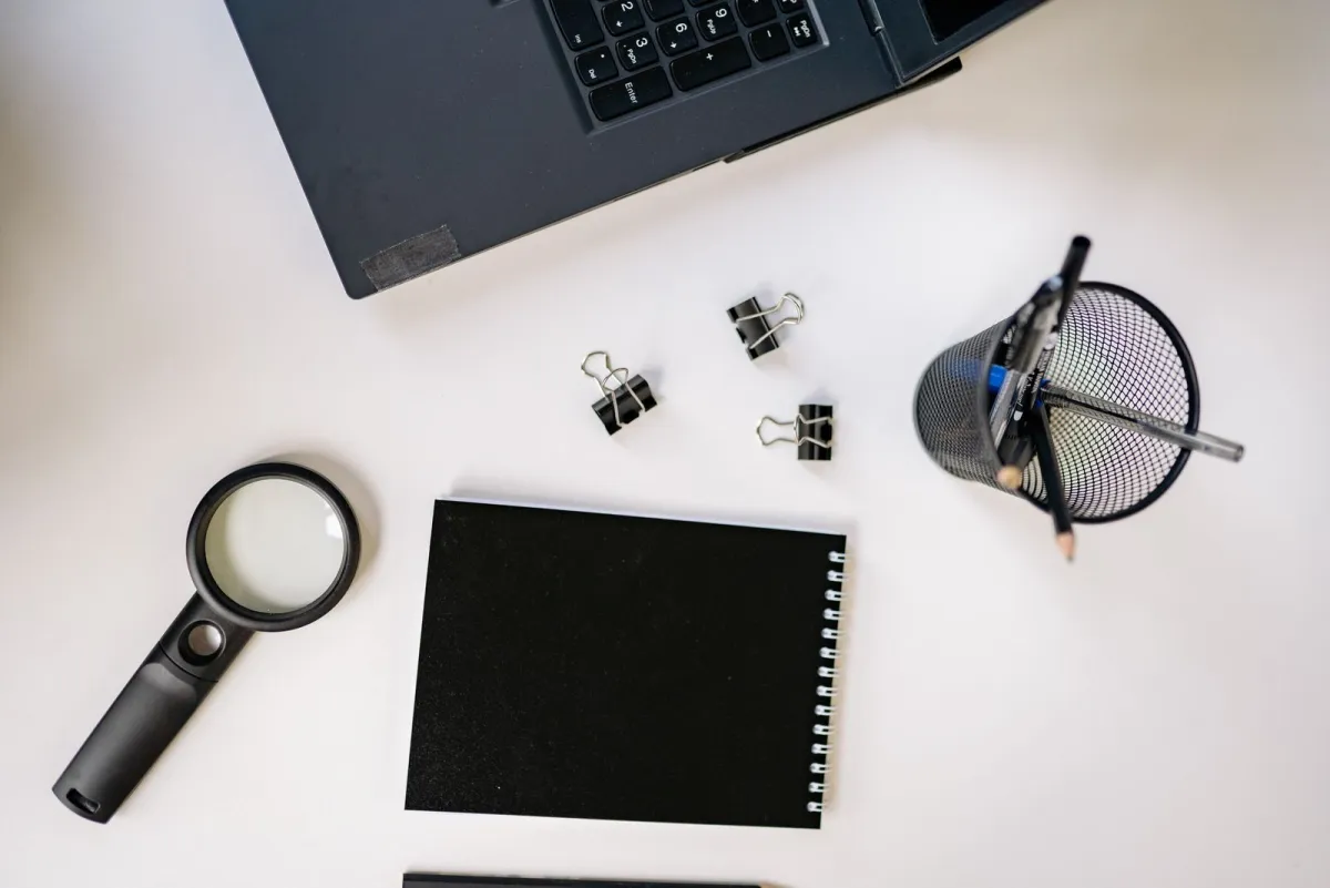 Laptop, notebook and magnifying glass on a white desk ready for keyword research