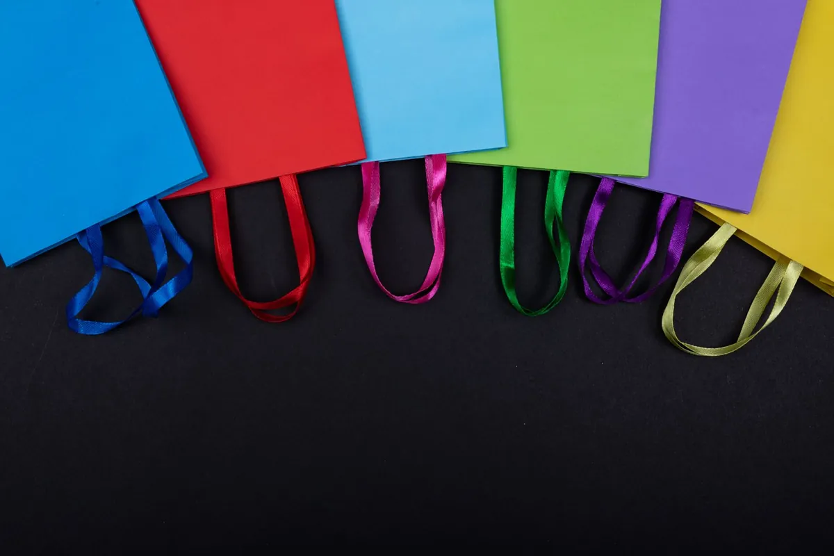 Colorful paper shopping bags lined up on a dark background