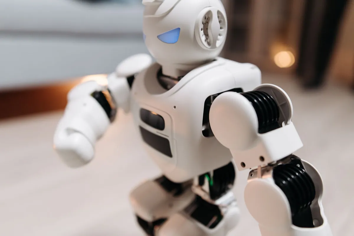 White toy robot with glowing blue eyes walking on a table