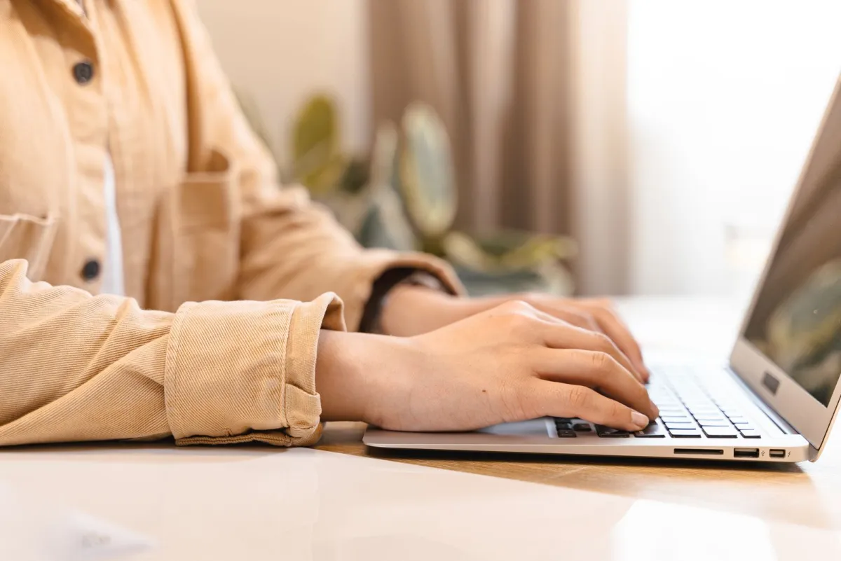 Schrijver die een artikelplan typt op een laptop aan een licht bureau