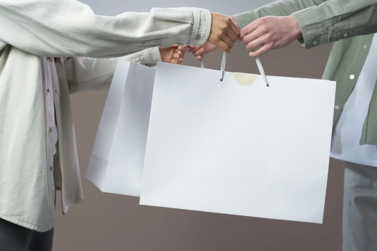 Two people handing over white shopping bags