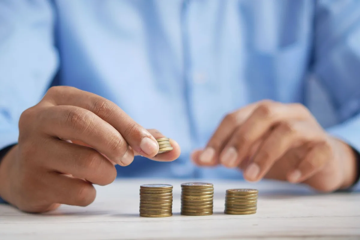 Hands stacking coins into small piles on a white table