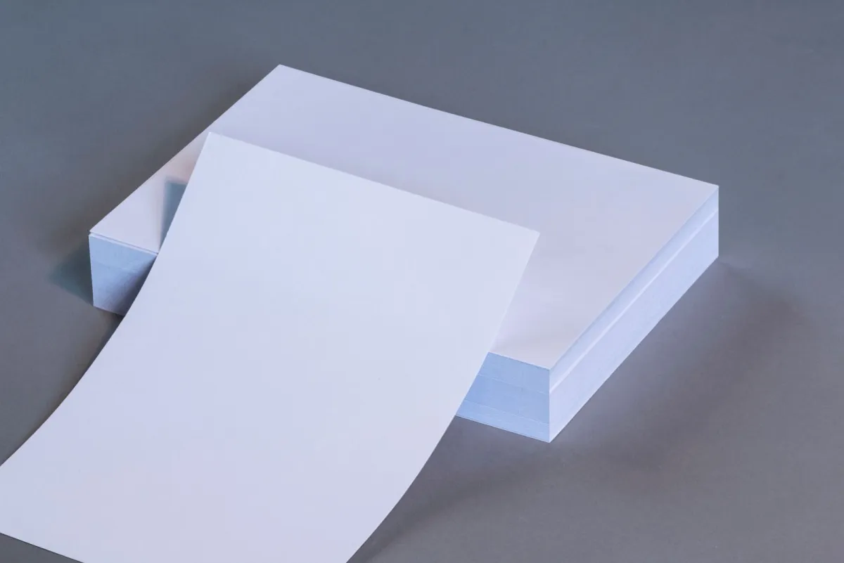 Stack of blank white paper sheets with the top sheet curling up
