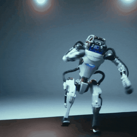 Boston Dynamics humanoid robot performing quick, dynamic movements in a studio setting with gray background and overhead lights.