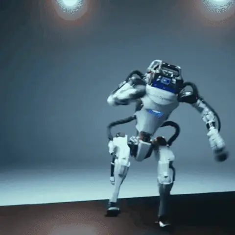 グレーの背景と天井照明のあるスタジオで、素早くダイナミックな動きを見せるBoston Dynamicsの人型ロボット